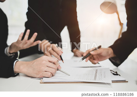 Cropped shot group of businesspeople analyzing data presented on a clipboard at meeting room Cropped shot group of businesspeople analyzing data presented on a clipboard at meeting room 118886186
