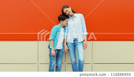 Happy smiling mother with son teenager posing together in casual clothing on orange wall background 118886950