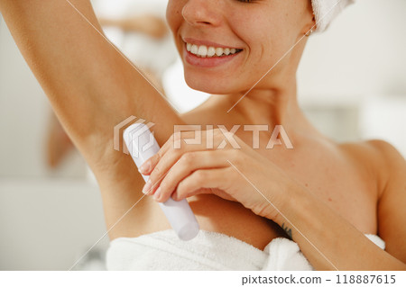 In a stylish bathroom, a woman applies deodorant to stay fresh and confident all day In a stylish bathroom, a woman applies deodorant to stay fresh and confident all day 118887615
