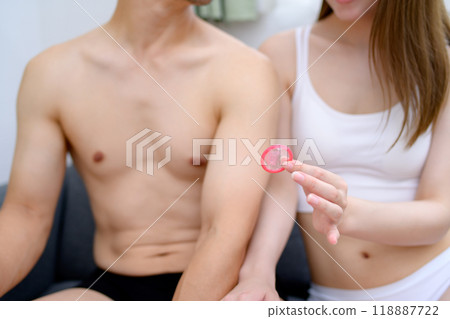 Woman recommending the use of contraception; Young woman's hand holding a condom; Male and female couple holding contraception; Married couple; Pregnancy planning; Sexual consent 118887722