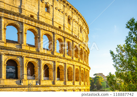 The ancient Colosseum stands majestically in Rome, illuminated by the warm glow of the evening sun. Visitors can explore its historic arches and vibrant surroundings, illustrating timeless beauty. The ancient Colosseum stands majestically in Rome, illuminated by the warm glow of the evening sun. Visitors can explore its historic arches and vibrant surroundings, illustrating timeless beauty. 118887742