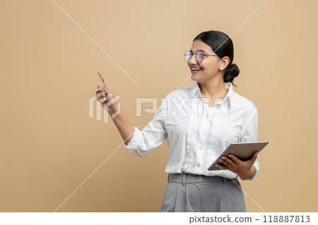 Satisfied woman holding digital tablet pointing at advertisement area Satisfied woman holding digital tablet pointing at advertisement area 118887813