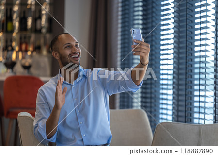 Friendly man in cafe having communication with video call on smartphone Friendly man in cafe having communication with video call on smartphone 118887890