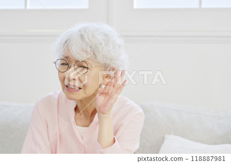 Hearing-impaired senior woman in the living room Hearing-impaired senior woman in the living room 118887981