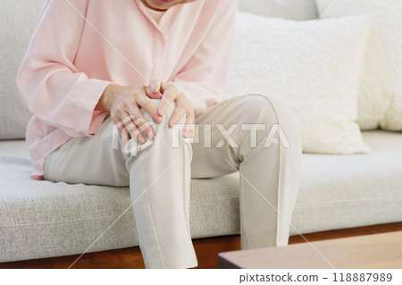 Senior woman with knee pain, living room, no face 118887989