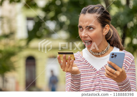 Shocked woman trying pay online shopping with smartphone blocked credit card lack of money balance Shocked woman trying pay online shopping with smartphone blocked credit card lack of money balance 118888398