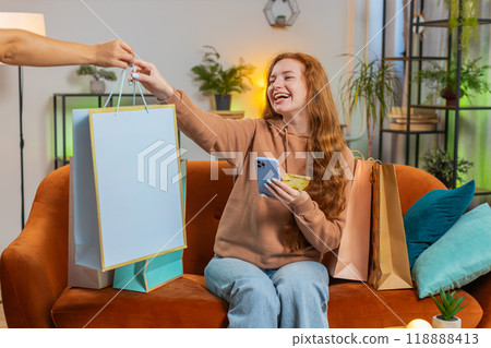 Excited young Caucasian woman with shopping bags receiving order sitting on sofa couch at home 118888413