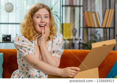 Happy young woman shopper unpacking cardboard box delivery parcel online shopping purchase at home Happy young woman shopper unpacking cardboard box delivery parcel online shopping purchase at home 118888423