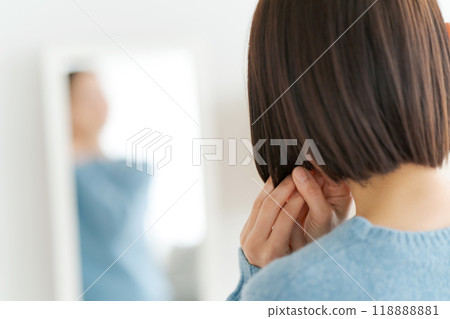 Woman looking in the mirror and fixing her hair Woman looking in the mirror and fixing her hair 118888881