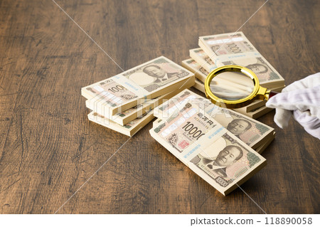 A stack of banknotes and a magnifying glass (new banknotes) 118890058