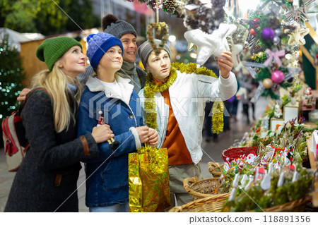 Winter holidays concept - happy mother, father and teenagers at christmas market Winter holidays concept - happy mother, father and teenagers at christmas market 118891356