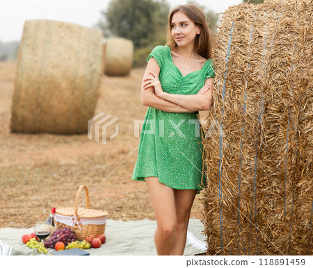 Young erotic beautiful woman in green dress posing near stack of straw in field Young erotic beautiful woman in green dress posing near stack of straw in field 118891459