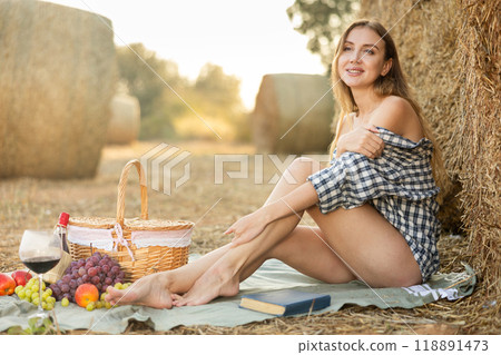 Young woman in shirt sitting during picnic Young woman in shirt sitting during picnic 118891473