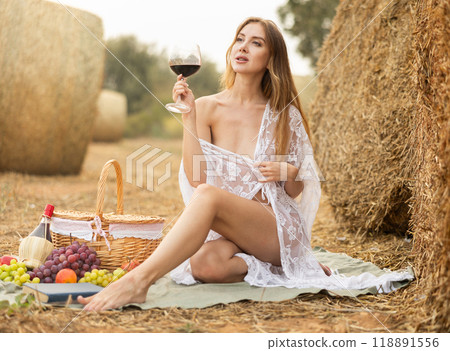 Woman sitting in peignoir with wine during picnic 118891556
