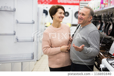 Happy spouses of mature age choose a refrigerator 118891640