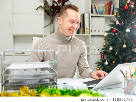 Cheerful man working in Christmas decorated office 118891791