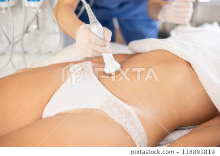 Female patient undergoing ultrasonic cavitation procedure on belly 118891819