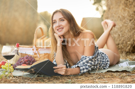 Woman in shirt lies reading book during picnic 118891820