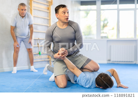 Man practicing painful armlock on male opponent at self defence training 118891821