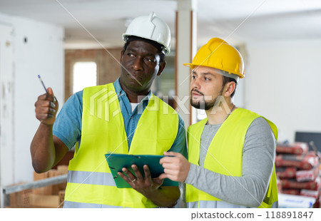 Two builders talking on indoor construction site 118891847