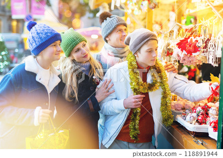 Winter holidays concept - happy mother, father and teenagers at christmas market Winter holidays concept - happy mother, father and teenagers at christmas market 118891944