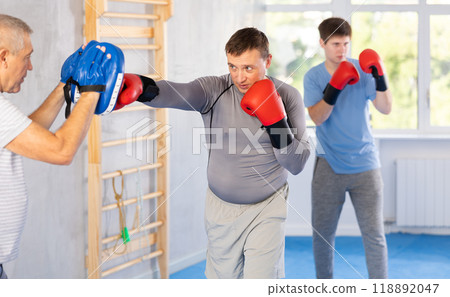 Man punching hits punch mitts is training with coach in box gym 118892047