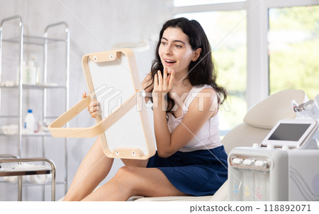 woman gazes at herself in mirror 118892071