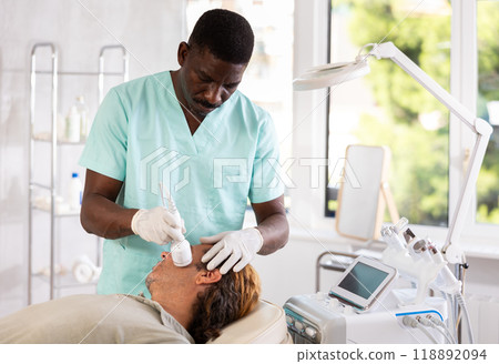 Man client undergoes facial skin care procedure using nozzle cold hammer whitening 118892094