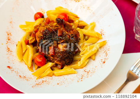 Chicken thigh fried with vegetables and herbs served with pasta 118892104