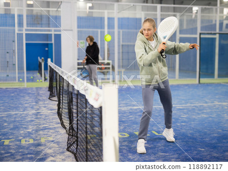 Active teen girl playing padel on tennis court 118892117