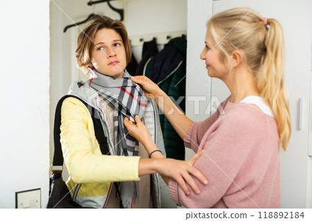 Impatient teenager stopping mother trying to straighten his scarf Impatient teenager stopping mother trying to straighten his scarf 118892184