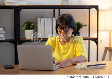 Senior asian woman working with writing on note and study while laptop on desk office. 118892381