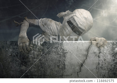 Mummy in bandages rising out of behind the wall, with a creepy, dark and scary mood. Ancient Egyptian mythology, devil, evil, satan, zombie Mummy in bandages rising out of behind the wall, with a creepy, dark and scary mood. Ancient Egyptian mythology, devil, evil, satan, zombie 118892575
