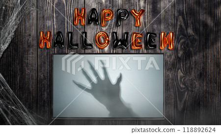 Shade of werewolf hands with fur and black claws on the screen with Happy Halloween balloon text on wooden background. Scary claw of werewolf, wolfman, or animal monster 118892624