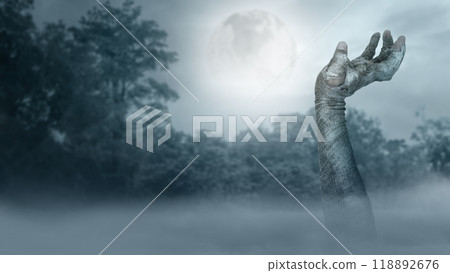 Mummy hand in bandages rising out of fog with a full moon in the background. Scene has dark and scary. The hand appearing to be a devil, evil, satan, zombie or a monster hand 118892676