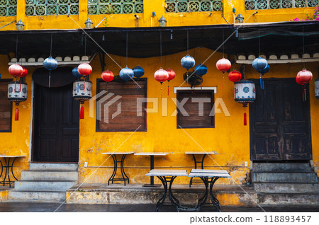 facade of an ancient Asian yellow cafe house decorated with Chinese hanging lanterns in old town in Hoi An in Vietnam in Asia 118893457