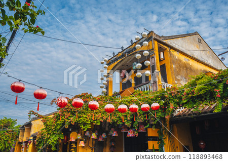 facade of an ancient Asian yellow house decorated with red Chinese lanterns for a holiday in old town in Hoi An in Vietnam 118893468