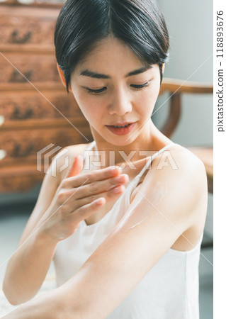 Young woman applying body cream to her arm 118893676
