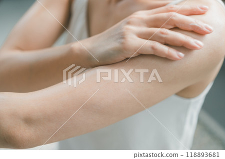 A woman applying body cream to her upper arms A woman applying body cream to her upper arms 118893681