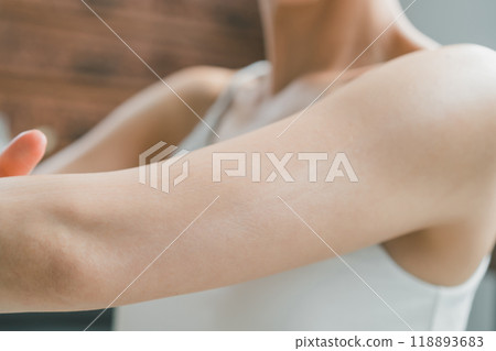 A woman applying body cream to her upper arms 118893683