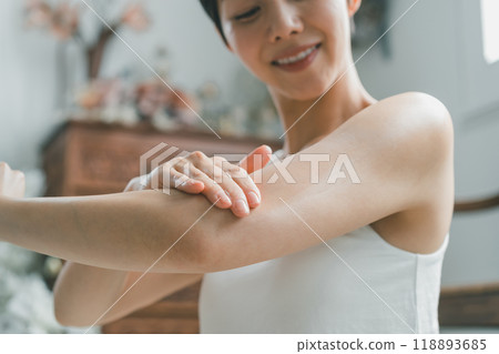 Young woman applying body cream to her arm Young woman applying body cream to her arm 118893685
