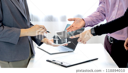 Real estate agents and a couple of buyers discuss signing a business contract, renting, buying, mortgage, loan or home insurance 118894010