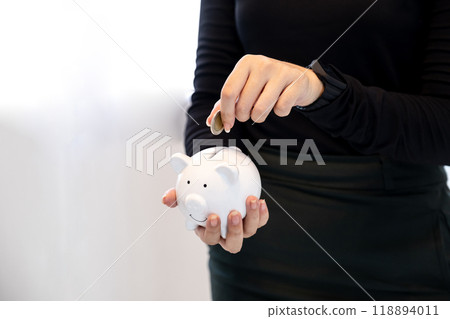 woman hand putting coin into white piggy bank, step up start up business to suscess, Saving money for future plan and retirement fund concept woman hand putting coin into white piggy bank, step up start up business to suscess, Saving money for future plan and retirement fund concept 118894011
