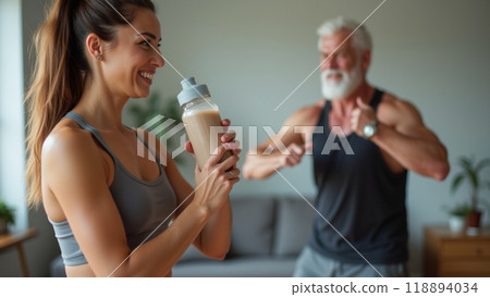 Young sporty woman with bottle of protein shake at home doing stretching exercise  118894034
