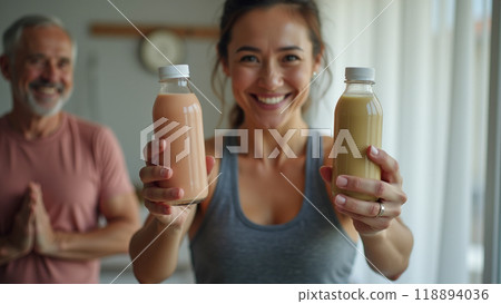 Young sporty woman with bottle of protein shake at home doing stretching exercise  118894036