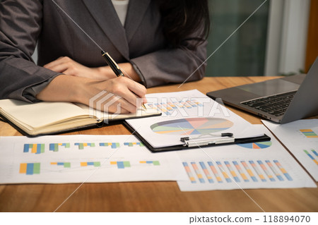 Businesswoman hand holding pen, analysis the graph with laptop at the home office for setting challenging business goals And planning to achieve the new target Businesswoman hand holding pen, analysis the graph with laptop at the home office for setting challenging business goals And planning to achieve the new target 118894070
