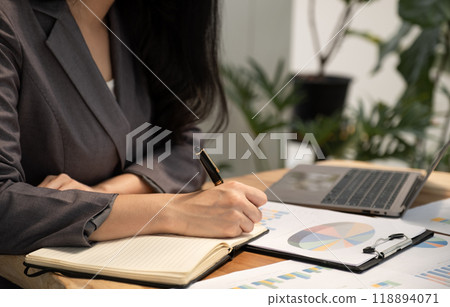 Businesswoman hand holding pen, analysis the graph with laptop at the home office for setting challenging business goals And planning to achieve the new target Businesswoman hand holding pen, analysis the graph with laptop at the home office for setting challenging business goals And planning to achieve the new target 118894071