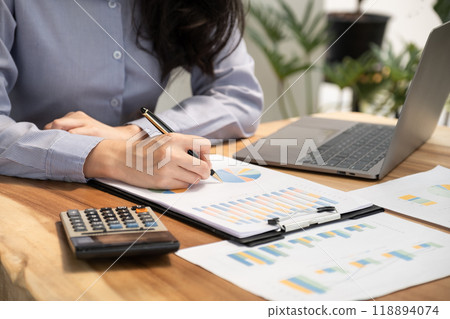 Businesswoman hand holding pen, analysis the graph with laptop at the home office for setting challenging business goals And planning to achieve the new target 118894074