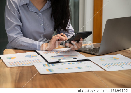 Businesswoman hand holding pen, analysis the graph with laptop at the home office for setting challenging business goals And planning to achieve the new target 118894102