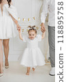 Happy toddler celebrating birthday with family in white attire 118895758